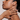 The side profile of a woman with beautiful smooth skin, she has her chin up and her left hand is against her neck.